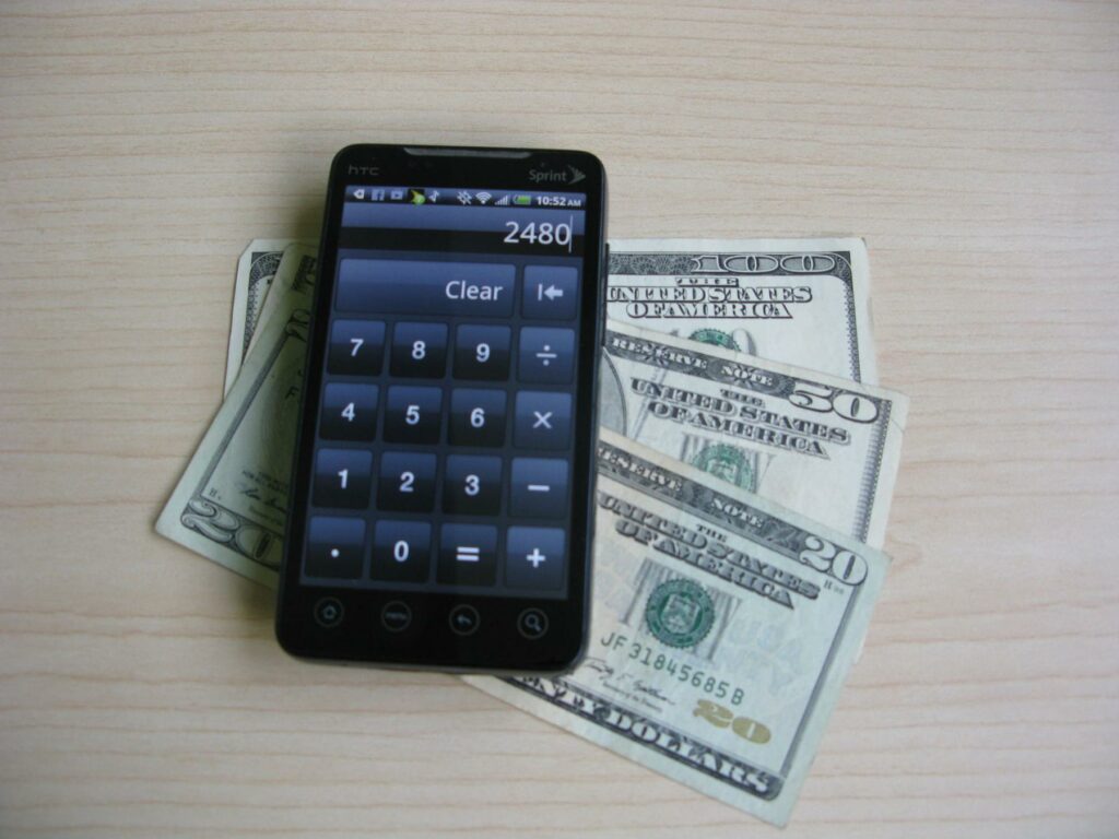 Android Smartphone with Money - a cell phone sitting on top of a pile of money
