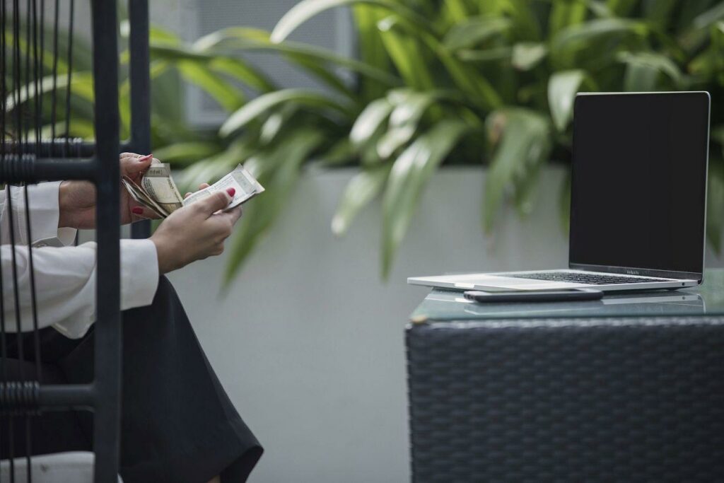 Free business person counting money - a woman sitting at a table with a laptop and a credit card