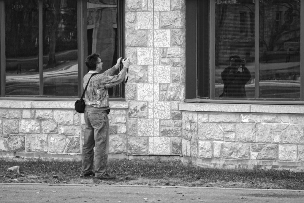 Self and reflection (8771120351) - a man standing in front of a building